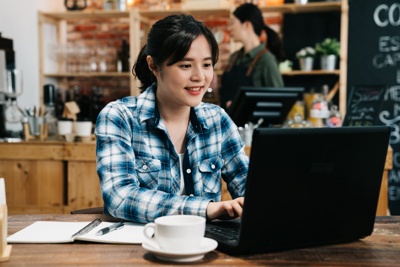 Image of happy asian young woman using laptop