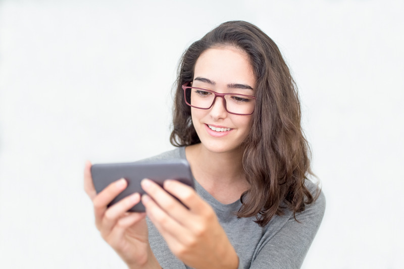Smiling teenage girl watching video on smartphone